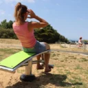 femme faisant des exercices d'abdominaux sur l'abdo inox face à la mer