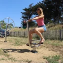 femme pédalant sur un vélo inox en bord de mer